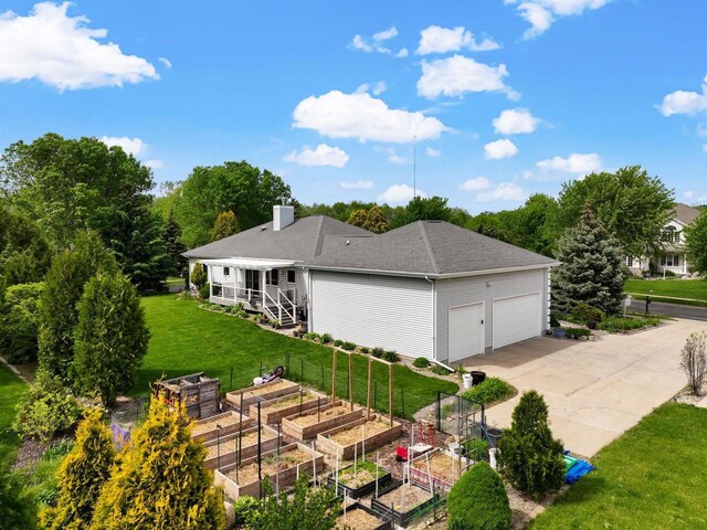 8705 Nelson Xing, Verona, WI 53593 - back of property featuring a vegetable garden, a yard, a garage, a chimney, and concrete driveway