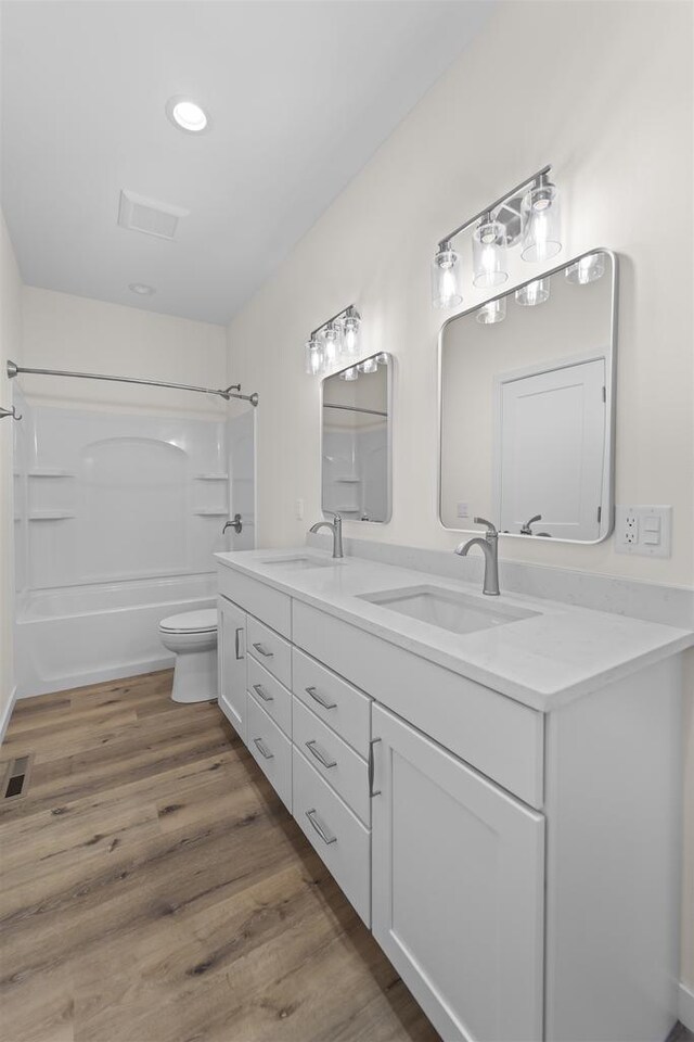 1407 Ridgetrail Dr, Cross Plains, WI 53528 - full bathroom with double vanity, shower / bathtub combination, toilet, wood finished floors, and recessed lighting