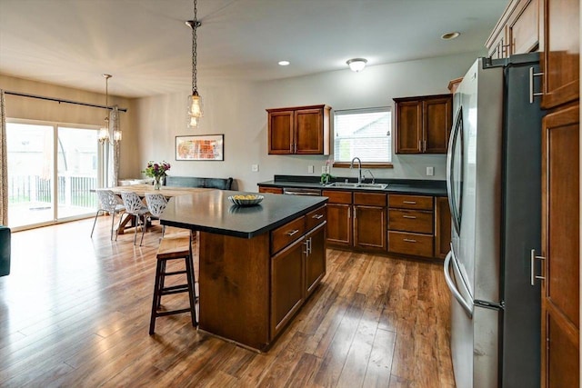 6972 Heirloom Dr, Deforest, WI 53532 - kitchen with freestanding refrigerator, a sink, dark countertops, a breakfast bar area, and dark wood-type flooring