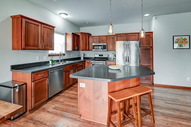 6972 Heirloom Dr, Deforest, WI 53532 - kitchen with stainless steel appliances, a sink, light wood-style flooring, a kitchen bar, and dark countertops
