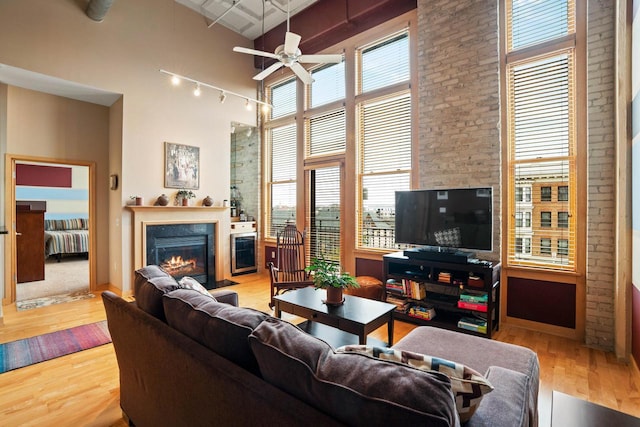 1325 N Van Buren St Unit 308, Milwaukee, WI 53202 - living area featuring a glass covered fireplace, wood-type flooring, rail lighting, ceiling fan, and a high ceiling