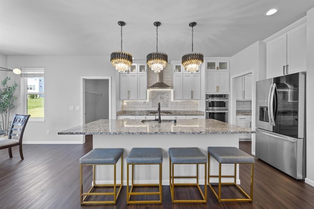 432 Tawny Elm Pkwy, Verona, WI 53593 - kitchen with appliances with stainless steel finishes, wall chimney range hood, a chandelier, tasteful backsplash, and dark wood-type flooring