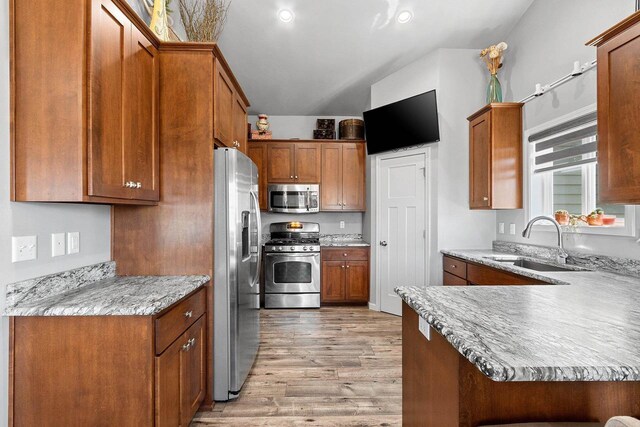 1397 Lear Ln, De Pere, WI 54115 - kitchen with stainless steel appliances, light wood finished floors, a sink, brown cabinetry, and a peninsula