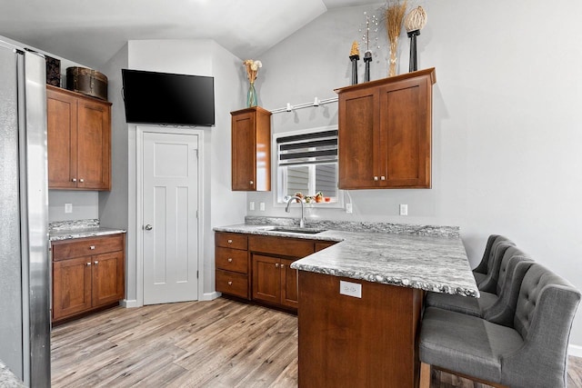 1397 Lear Ln, De Pere, WI 54115 - kitchen with a sink, a peninsula, light wood-style flooring, a kitchen breakfast bar, and vaulted ceiling