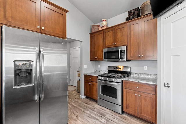 1397 Lear Ln, De Pere, WI 54115 - kitchen with stainless steel appliances, light wood finished floors, light stone countertops, brown cabinetry, and lofted ceiling