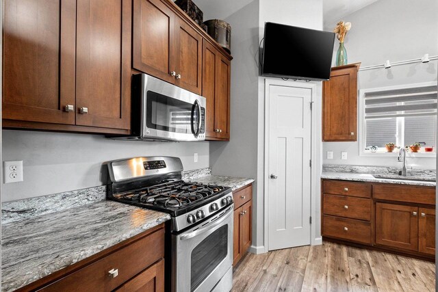 1397 Lear Ln, De Pere, WI 54115 - kitchen featuring appliances with stainless steel finishes, a sink, light wood-style flooring, light stone counters, and brown cabinetry
