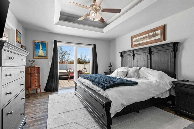 1397 Lear Ln, De Pere, WI 54115 - bedroom featuring access to exterior, light wood-style flooring, a tray ceiling, and ceiling fan