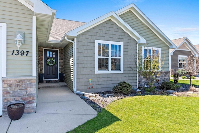 1397 Lear Ln, De Pere, WI 54115 - view of exterior entry featuring a yard, a shingled roof, and stone siding
