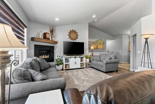 1397 Lear Ln, De Pere, WI 54115 - living room with wood finished floors, lofted ceiling, a warm lit fireplace, baseboards, and recessed lighting
