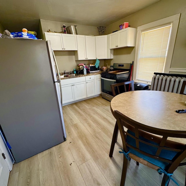 2664 N Booth St, Milwaukee, WI 53212 - kitchen with stainless steel appliances, light wood-style flooring, white cabinetry, and a sink