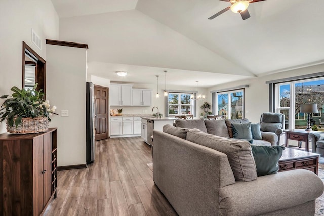 5208 Briarwood Cir, Racine, WI 53402 - living room featuring light wood finished floors, a ceiling fan, high vaulted ceiling, and a chandelier