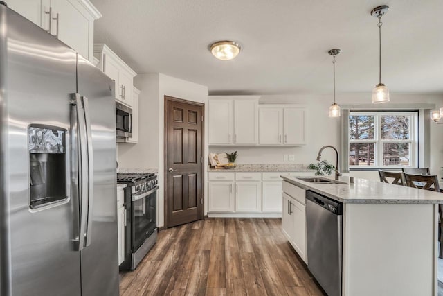 5208 Briarwood Cir, Racine, WI 53402 - kitchen featuring appliances with stainless steel finishes, a sink, dark wood-style flooring, white cabinets, and a center island with sink
