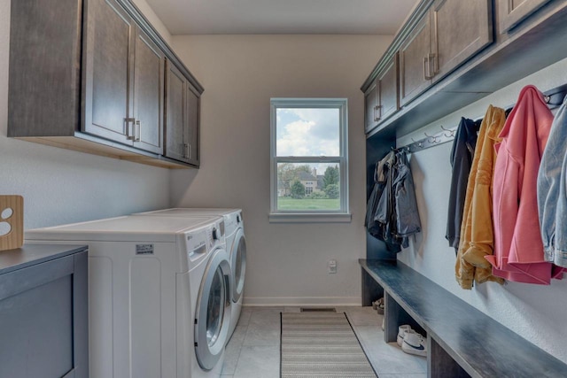 laundry room with independent washer and dryer, cabinet space, light tile patterned floors, and baseboards