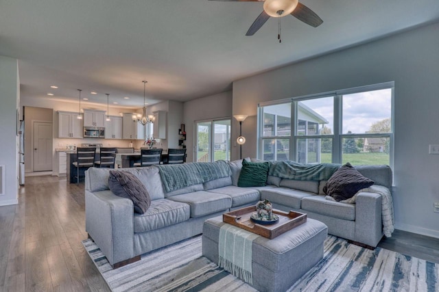 living room with a chandelier, wood finished floors, baseboards, recessed lighting, and a ceiling fan