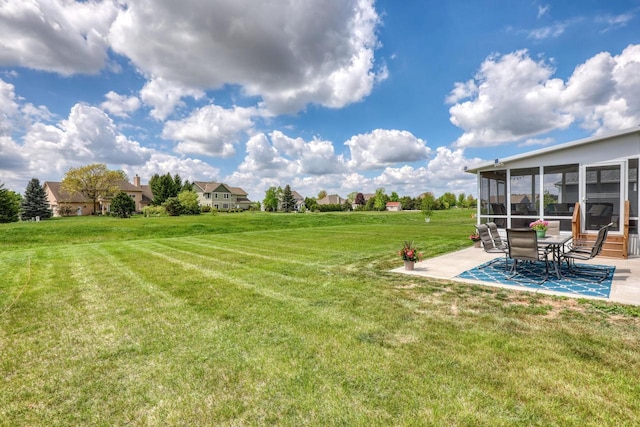 view of grassy yard featuring a patio area and a sunroom
