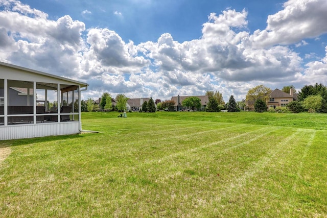 view of grassy yard featuring a sunroom