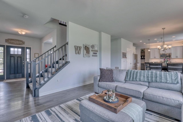 living room featuring a chandelier, dark wood-type flooring, stairway, baseboards, and recessed lighting