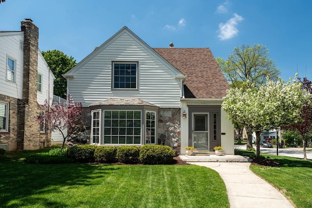 2577 N 89th St, Wauwatosa, WI 53226 - traditional-style home featuring a front lawn, a shingled roof, and stone siding
