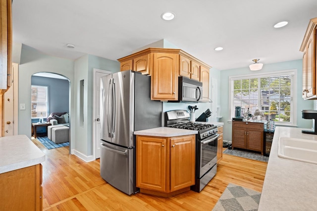 2577 N 89th St, Wauwatosa, WI 53226 - kitchen featuring stainless steel appliances, arched walkways, light wood-style floors, light countertops, and recessed lighting