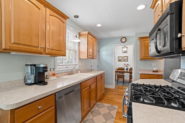 2577 N 89th St, Wauwatosa, WI 53226 - kitchen with appliances with stainless steel finishes, a sink, light countertops, hanging light fixtures, and light wood-style flooring