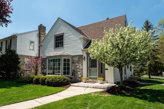 2577 N 89th St, Wauwatosa, WI 53226 - view of front of house with a front yard, a chimney, and stone siding