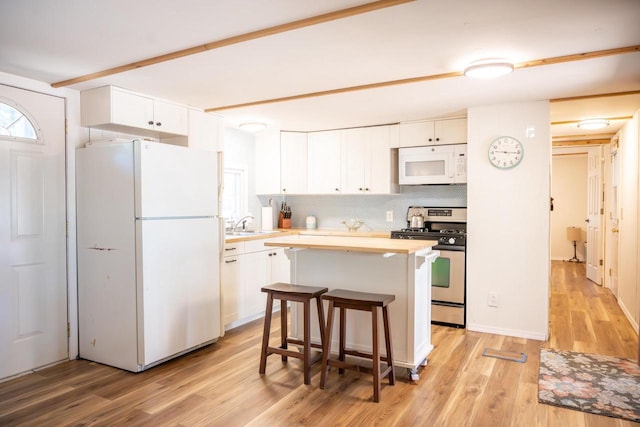 984 E Trout Valley Rd, Friendship, WI 54646 - kitchen with white appliances, light wood-type flooring, white cabinetry, a center island, and backsplash