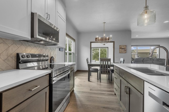 3153 Lazy Oak Ct, Green Bay, WI 54311 - kitchen with stainless steel appliances, a sink, a chandelier, backsplash, and decorative light fixtures