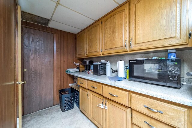 5908-5910 Edward St, Weston, WI 54476 - kitchen featuring black microwave, a paneled ceiling, brown cabinetry, light stone countertops, and wooden walls