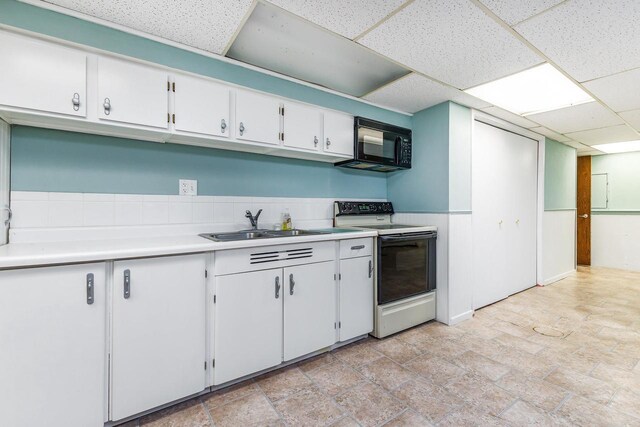 11915 Wedgewood Ln, Darlington, WI 53530 - kitchen with range with electric stovetop, black microwave, a sink, light countertops, and white cabinetry