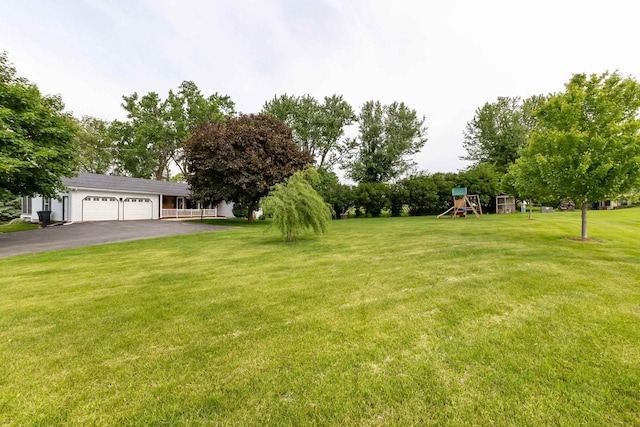 11915 Wedgewood Ln, Darlington, WI 53530 - view of grassy yard featuring a playground, an attached garage, and driveway