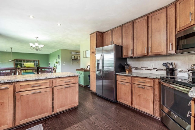 11915 Wedgewood Ln, Darlington, WI 53530 - kitchen featuring stainless steel appliances, dark wood finished floors, a chandelier, brown cabinets, and light stone counters