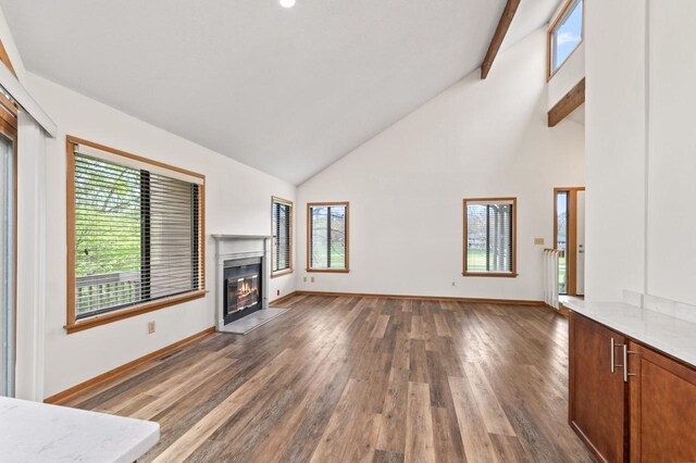 901 Duck Pond Rd, Fontana, WI 53125 - unfurnished living room featuring high vaulted ceiling, plenty of natural light, wood finished floors, a glass covered fireplace, and baseboards