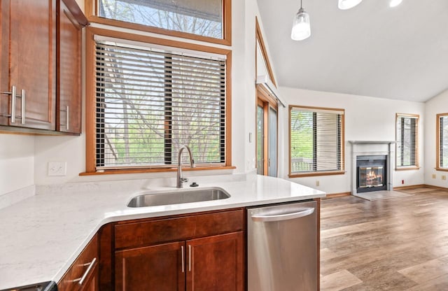 901 Duck Pond Rd, Fontana, WI 53125 - kitchen with stainless steel dishwasher, a sink, open floor plan, a fireplace with flush hearth, and light stone countertops