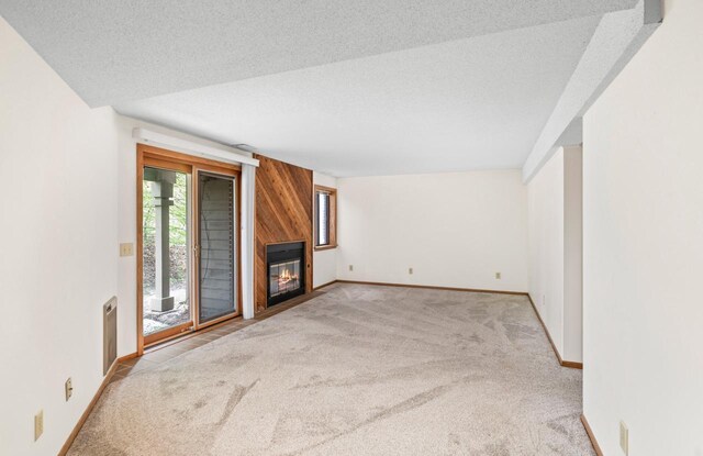 901 Duck Pond Rd, Fontana, WI 53125 - unfurnished living room featuring carpet, baseboards, a textured ceiling, a large fireplace, and wood walls
