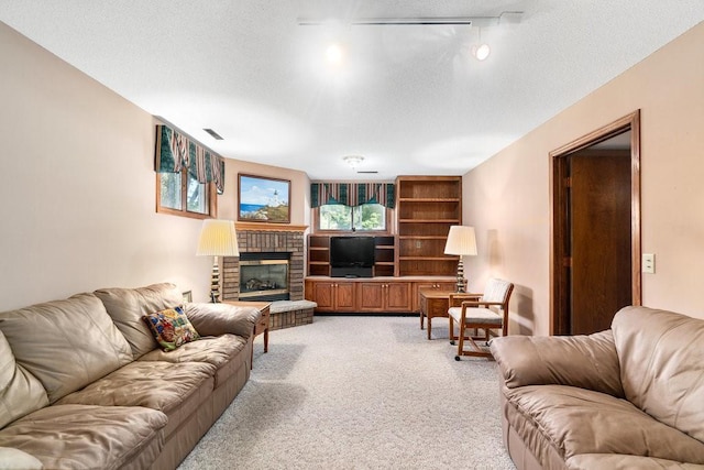 living area featuring light colored carpet, a textured ceiling, a brick fireplace, and track lighting