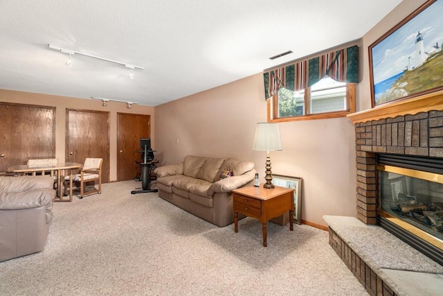 living room featuring track lighting, carpet, and a fireplace