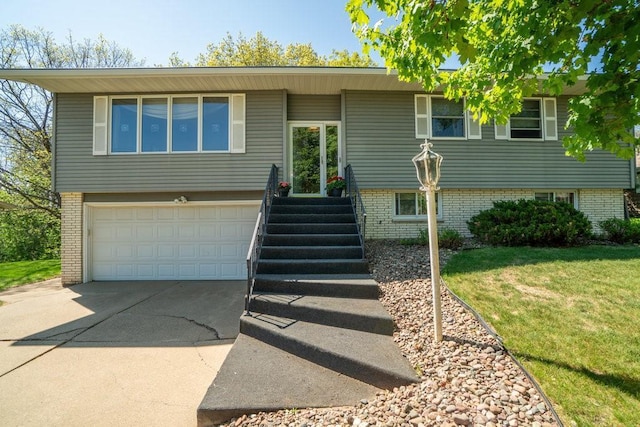 split foyer home featuring driveway, a garage, brick siding, and a front yard