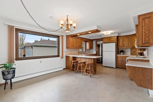 1020 W 3rd St, Kimberly, WI 54136 - kitchen featuring freestanding refrigerator, brown cabinets, a chandelier, and a baseboard radiator