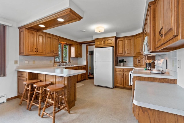 1020 W 3rd St, Kimberly, WI 54136 - kitchen featuring freestanding refrigerator, brown cabinets, a peninsula, backsplash, and a sink