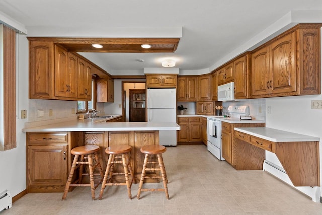 1020 W 3rd St, Kimberly, WI 54136 - kitchen featuring white appliances, a baseboard radiator, a peninsula, brown cabinets, and light countertops