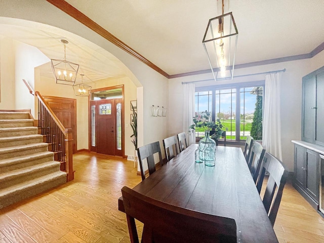 5634 Wind Dancer Ct, Sheboygan, WI 53081 - dining space featuring a chandelier, arched walkways, light wood-type flooring, stairs, and ornamental molding