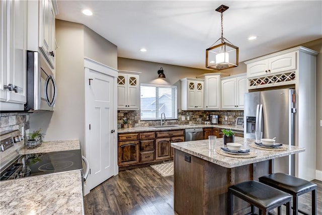 1215 Brooke Ct, Chippewa Falls, WI 54729 - kitchen with appliances with stainless steel finishes, a sink, a kitchen breakfast bar, backsplash, and dark wood-type flooring