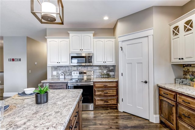 1215 Brooke Ct, Chippewa Falls, WI 54729 - kitchen featuring stainless steel appliances, white cabinetry, dark wood-style floors, tasteful backsplash, and light stone countertops