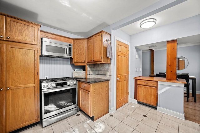 530 W Acacia Rd, Glendale, WI 53217 - kitchen featuring stainless steel appliances, decorative backsplash, light tile patterned floors, and baseboards