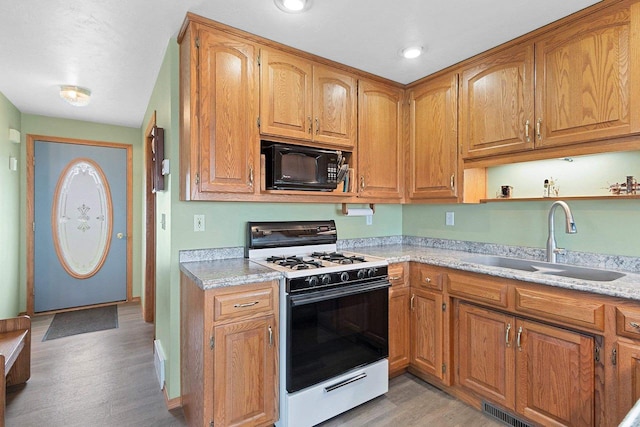 N3351 County Road B, Kewaunee, WI 54216 - kitchen with white gas stove, black microwave, a sink, light wood-type flooring, and light countertops