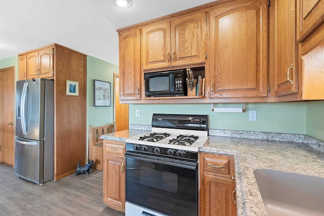 N3351 County Road B, Kewaunee, WI 54216 - kitchen featuring gas range, stainless steel fridge, light wood-style floors, black microwave, and a sink