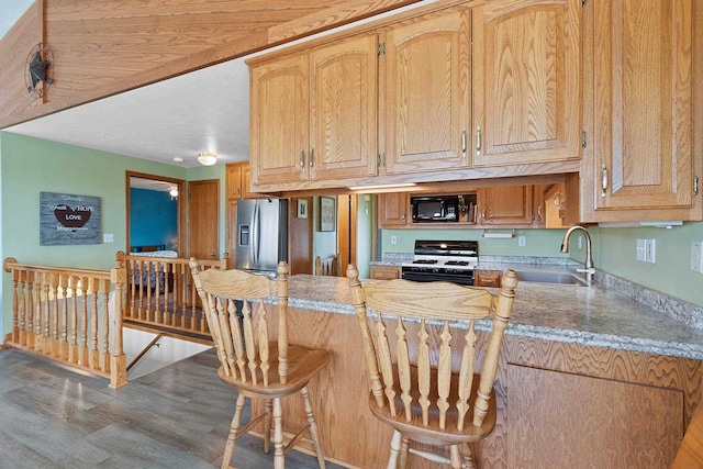 N3351 County Road B, Kewaunee, WI 54216 - kitchen featuring white range with gas stovetop, black microwave, stainless steel fridge, wood finished floors, and a breakfast bar area