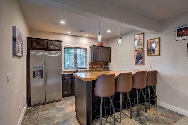 1002 Millies Way, Waunakee, WI 53597 - kitchen featuring stainless steel fridge with ice dispenser, baseboards, stone finish flooring, a breakfast bar, and recessed lighting