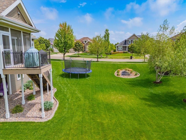 1002 Millies Way, Waunakee, WI 53597 - view of green lawn with a sunroom, stairs, a trampoline, a wooden deck, and a residential view