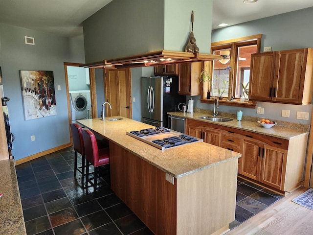 W7429 Akron Dr, Wild Rose, WI 54984 - kitchen with appliances with stainless steel finishes, a sink, washer / dryer, a kitchen island with sink, and recessed lighting